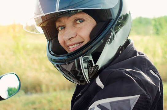 Attractive Woman 60 Years Old In A Motorcycle Helmet Looking At The Camera. Close-up Portrait.