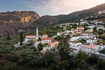 Fototapeta na wymiar Greek village with white houses on hill slope and mountain gorge in the background, Crete, Greece