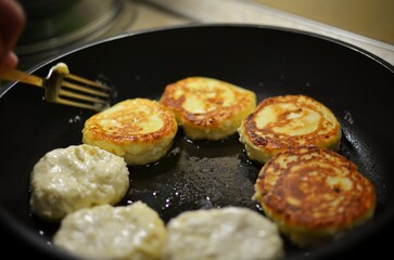 Woman cooks cheesecakes on the pan with oil