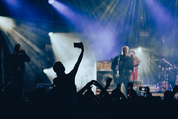 Silhouette of a woman using smartphone on a concert