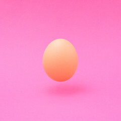 Minimal Easter concept. An egg levitating above a intense pink background