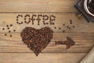 Coffee beans text and arrow, heart shape on an old wooden background and vintage coffee mill. Coffee design concept.