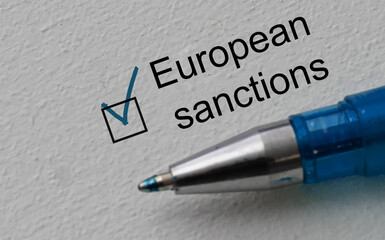 check mark on the word sanctions and pen. Closeup, concept