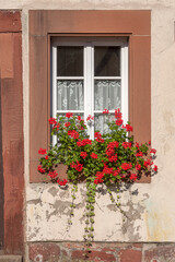Fototapeta na wymiar Kleines Fenster mit Blumenschmuck