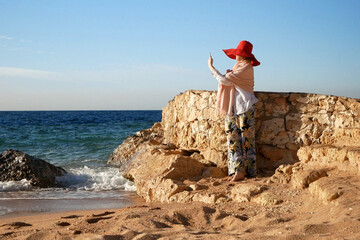 Summer vacation woman in red hat on the sea beach with mobile phone, woman blogger