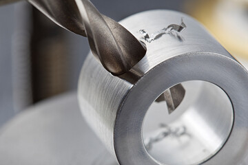 metal drill bit make holes in aluminium pipe on industrial drilling machine. Metal work industry.