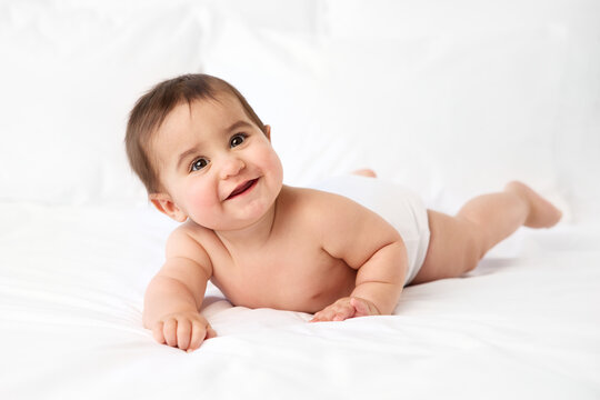 Smiling baby boy lying on tummy on bed