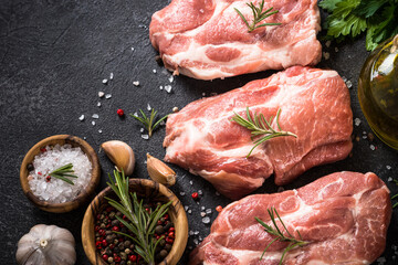 Fresh pork steaks with spices at black background. Top view with copy space.