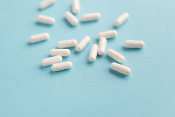 White capsule pills on a blue background. Medical background with copy space for text.