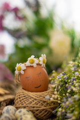 Fototapeta na wymiar Easter card. Smiling rashal egg in a wreath of flowers close-up on a photo of flowers