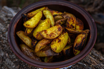 Homemade crispy potatoes on a frying pan on the fire outside. Picnic in nature with cooking.