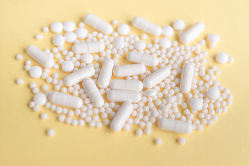 Fototapeta na wymiar White pills on a pastel background. Capsules and round pills close-up. Healthcare and medicine. 