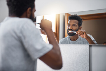 Hes a firm believer in brushing twice a day. Cropped shot of a handsome young man brushing his...
