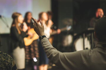 Hands in the air of a woman who praise God at church service - obrazy, fototapety, plakaty