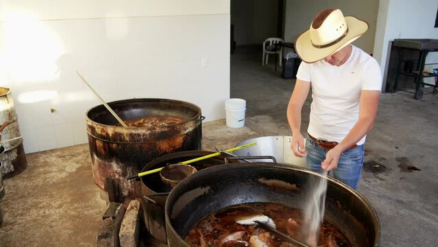Muchacho se&ntilde;or trabajador preparando haciendo y cocinando rico y delicioso platillo t&iacute;pico carnitas comida carne de cerdo puerco en manteca aceite