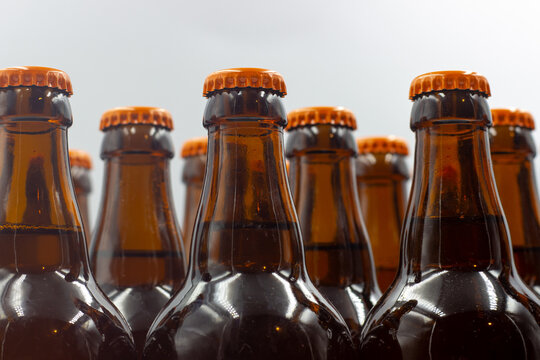 Isolated homemade craft beer bottles with white background. Close-up photo of the beer bottles with orange caps. Isolated beer bottles with orange caps. Topside view.