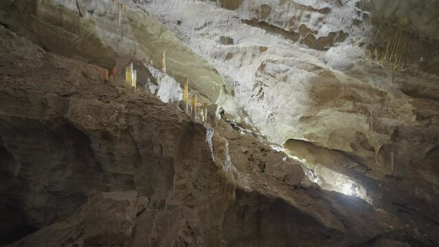Underground cave formations of stalactites and stalagmites. Action. View inside of a cavern on giant stone walls.
