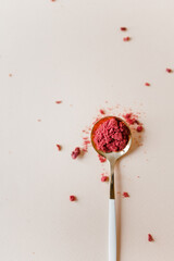 Dried raspberries and raspberry powder is scattered and lies on a small spoon