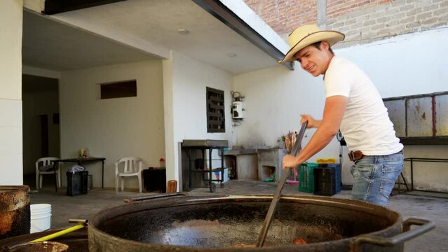 Muchacho se&ntilde;or trabajador preparando haciendo y cocinando rico y delicioso platillo t&iacute;pico carnitas comida carne de cerdo puerco en manteca aceite