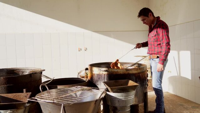 Muchacho se&ntilde;or trabajador preparando haciendo y cocinando rico y delicioso platillo t&iacute;pico carnitas comida carne de cerdo puerco en manteca aceite