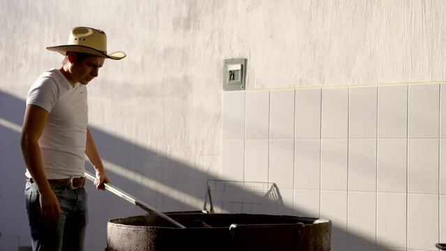 Muchacho se&ntilde;or trabajador preparando haciendo y cocinando rico y delicioso platillo t&iacute;pico carnitas comida carne de cerdo puerco en manteca aceite