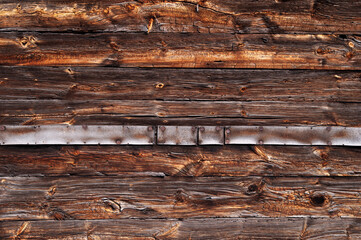 Texture of old wood with natural patterns. A metal plate with traces of rust is nailed in the middle.