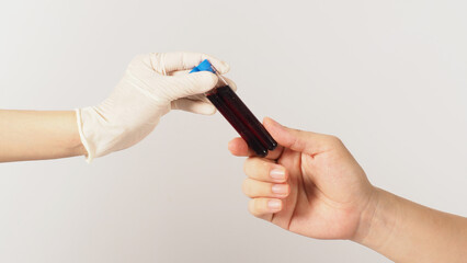 Two hands send and receive two blood test tubes on white background. One hand wear latex glove.