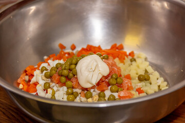 The chef prepares Olivier salad, mixes all the ingredients and adds mayonnaise