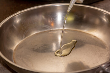 The cook pours oil on a steel pan for frying