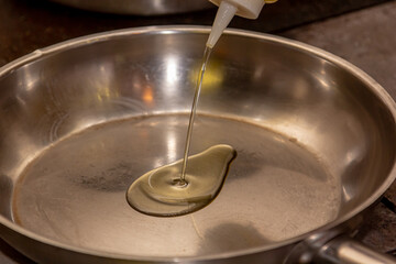 The cook pours oil on a steel pan for frying