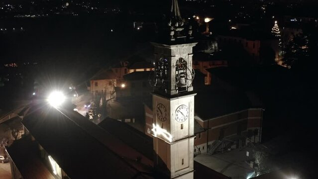 Beautiful night aerial copter 4k footage of illuminated catholic medieval church with belfry tower with clocks and decorated Christmas figures on the hill