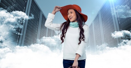 Asian woman wearing a hat smiling against computer servers and clouds
