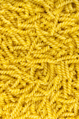 Raw pasta fusilli. spiral shape pasta, yellow background