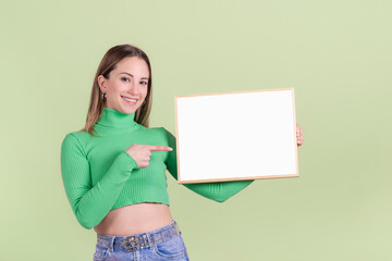 Smiling blonde woman pointing at a blank white chalkboard