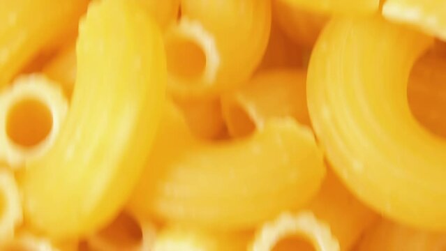 Uncooked Chifferi Rigati Pasta - Top View, Close-Up. Fat and Unhealthy Food. Classic Dry Macaroni, Moving Upward Background. Italian Culture and Cuisine. Raw Golden Pasta Texture in Move