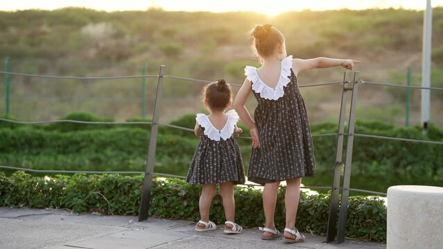 Niñas amigas hermanas con vestido felices viendo en el parque un hermoso atardecer juntas dando un paseo al aire libre en el exterior disfrutando felices jugando divertidas