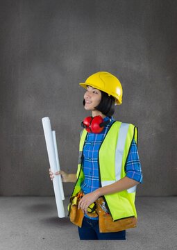 Asian female architect holding plans against copy space on grey background