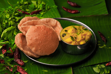 south indian famous breakfast poori or puri with potato curry served in a plate with banana leaf closeup with selective focus and blur - obrazy, fototapety, plakaty