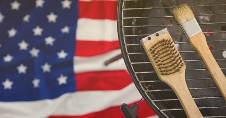 Close up of multiple tools over a barbeque against american flag in background