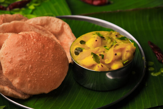 south indian famous breakfast poori or puri with potato curry served in a plate with banana leaf closeup with selective focus and blur