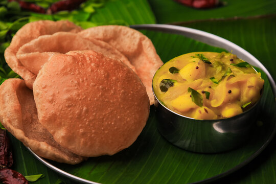 south indian famous breakfast poori or puri with potato curry served in a plate with banana leaf closeup with selective focus and blur