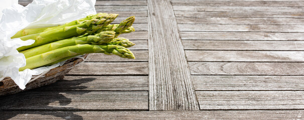 Fresh green asparagus on a wooden market counter. Horizontal background for the seasonal gastronomy with space for text.