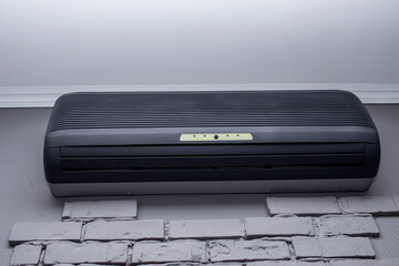 modern black air conditioner hanging on white brick wall