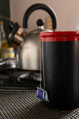 Detalle de bolsas de Té en taza roja con tetera de fondo