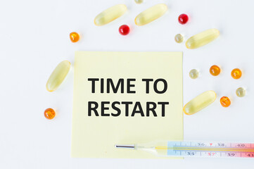 Text TIME TO RESTART on a yellow card for notes on a white table next to scattered color tablets...