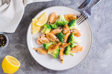 Fried broccoli and shrimp on a plate on the table. Top view. Close-up