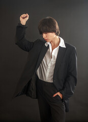 Portrait of sad and sorrow young woman on black background in business suit of an office worker, manager