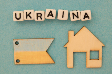 Napis Ukraina leżący nad drewnianym domem i flagą Ukrainy - symboliczne znaczenie - obrazy, fototapety, plakaty