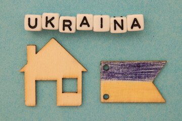 Napis Ukraina leżący nad drewnianym domem i flagą Ukrainy - symboliczne znaczenie - obrazy, fototapety, plakaty