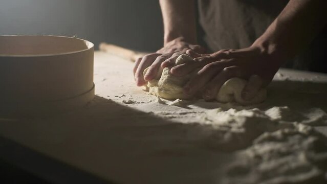 Close-up, hands of a cook in a bakery kneading dough and preparing bread according to a traditional recipe, isolated on a black background